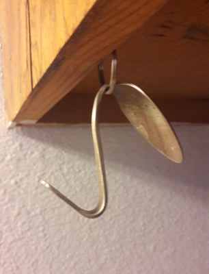 Slide thin end of spoon through ring (which is hanging from an eye hook